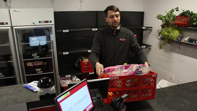 Robin Schmieding, Rewe-Marktleiter  im Aischpark-Center, befindet sich in der Abholstation. Er zeigt eine Kiste für einen Kunden, der Waren online bestellt hatte. Dies sei sehr begehrt momentan.  Foto: Christian Bauriedel