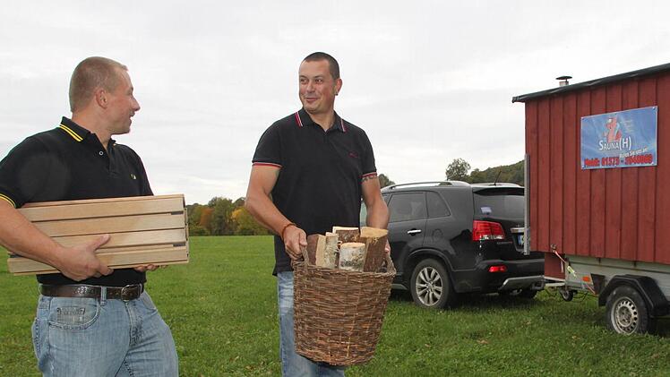 Bernd Lattner (links) und Stefan Wagner bestücken die mobile Sauna mit einem Korb Holz und der Fußmatte. Foto: Stephan Tiroch