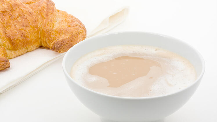 Caf&eacute; au lait mit Buttercroissant vor wei&szlig;em Hintergrund Cafe au lait with butter croissant over white background