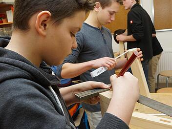Thomas Efremov und Lukas Graf messen mit Winkel und Zollstock ein Kantholz aus. Foto: Arkadius Guzy