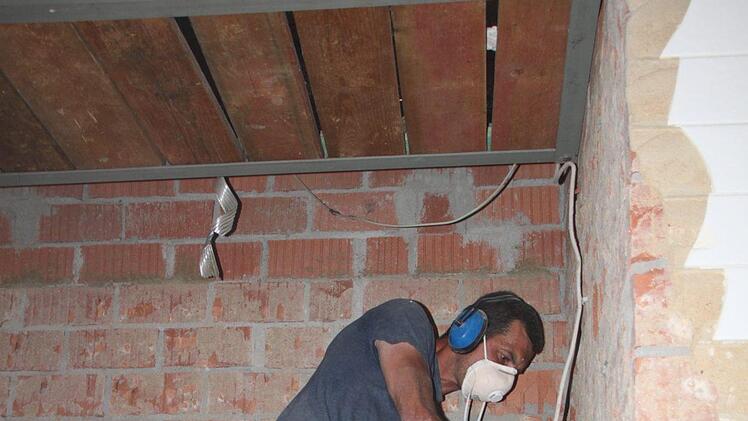 Mit der Hand stemmen die Bauarbeiter den Putz von den Wänden. Foto: Ulrike Müller
