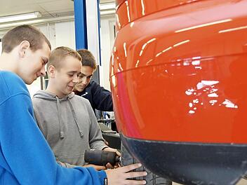 Die angehenden Kfz-Mechaniker Kristian Zygadlo, Piotr Miroszewski und Mateusz Walkosz wechseln einen Autoreifen in der Ausbildungswerkstatt auf dem Lagerberg. Foto: Arkadius Guzy