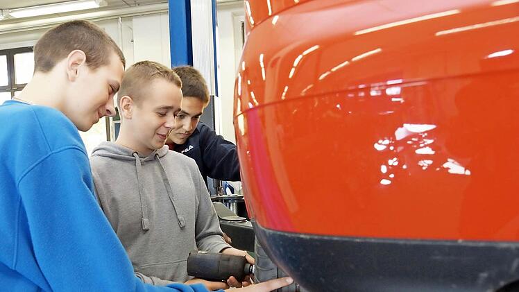 Die angehenden Kfz-Mechaniker Kristian Zygadlo, Piotr Miroszewski und Mateusz Walkosz wechseln einen Autoreifen in der Ausbildungswerkstatt auf dem Lagerberg. Foto: Arkadius Guzy