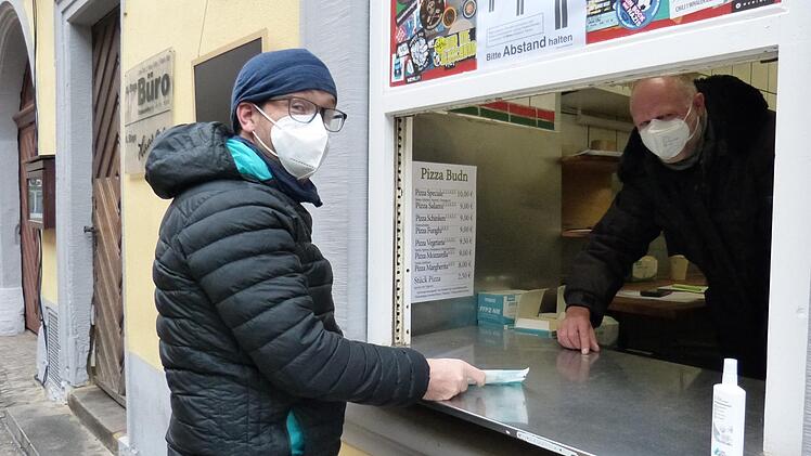 Volker Wrede (rechts) verkauft FFP2-Masken am Fenster, wo früher Pizzastücke bei Nacht ausgegeben wurden. Foto: Julian Megerle