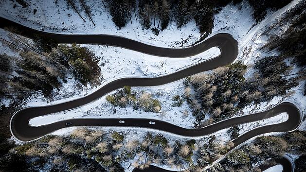 Reise, Winterreifen - Aerial view of a car serpentine on a mountain . Road to La Thuile village and ski area . Snowy mountain serpentine in Aosta valley in Italy .
