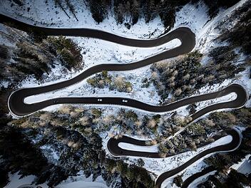 Reise, Winterreifen - Aerial view of a car serpentine on a mountain . Road to La Thuile village and ski area . Snowy mountain serpentine in Aosta valley in Italy .