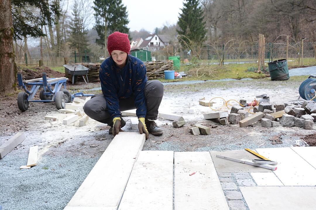 Platten verlegen: Die schmalen Fugen werden erst mit Splitt, am Ende mit Brechsand gefüllt.Teamwork