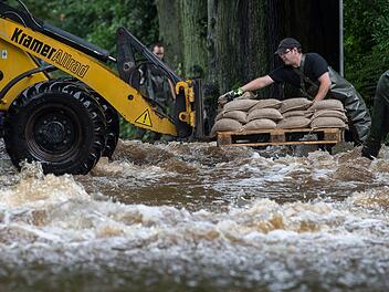 Feuerwehrm&auml;nner laden am 26.07.2017 in Holzminden (Niedersachsen) Sands&auml;cke von einem Radlader ab. Wie hier kam es in vielen teilen Deutschlands zu &Uuml;berschwemmungen - und eine Entspannung der Lage ist erst einmal nicht in Sicht. Foto: Silas Stein/dpa