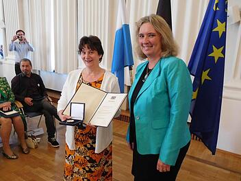Heidrun Mücke zeigt Ehrenmedaille und -urkunde, die sie von Staatsministerin Kerstin Schreyer verliehen bekommen hat. Foto: Gert Krautbauer/StMAS