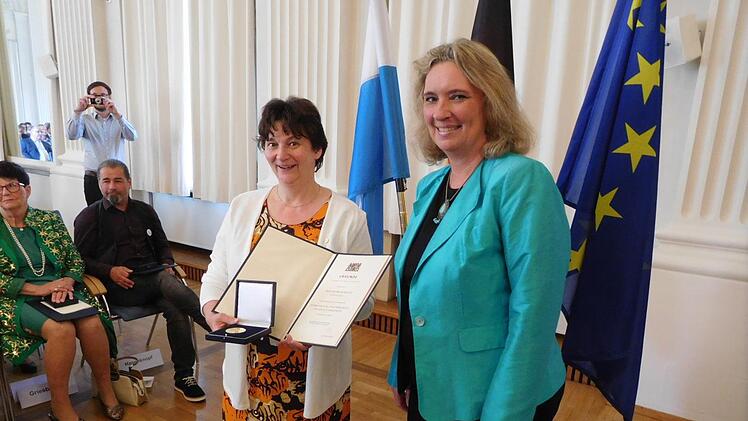 Heidrun Mücke zeigt Ehrenmedaille und -urkunde, die sie von Staatsministerin Kerstin Schreyer verliehen bekommen hat. Foto: Gert Krautbauer/StMAS