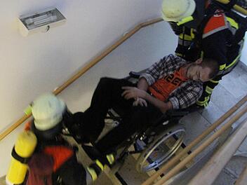Keine einfache Sache: Die Bergung eines Rollstuhlfahrers und dessen Transport durch das Treppenhaus. Doch die Rettungskräfte meisterten bei der Großübung im Stadtsteinacher Seniorenheim auch diese Aufgabe mit Bravour. Foto: Sonja Adam