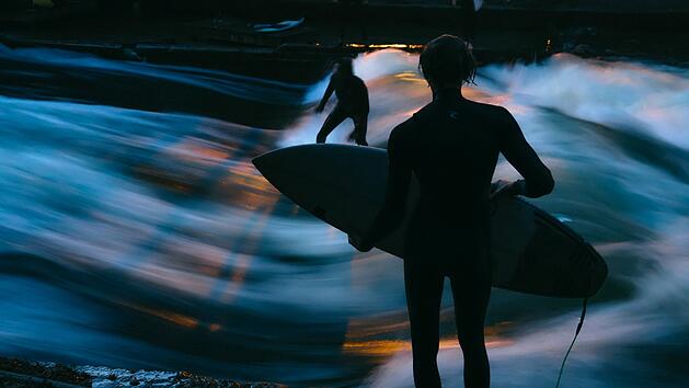 Wellenreiter an M&uuml;nchens ber&uuml;hmter Eisbachwelle, K&uuml;nstliche stehende Welle im Eisbach des Englischen Gartens, die ganzj&auml;hrig zum Surfen einl&auml;dt.