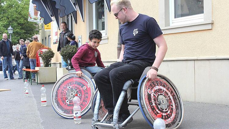 Johannes Vogl aus Edelbrunn (rechts) zeigte den Besuchern beim Frühlingsfest in Haßfurt wie es ist, mit einem Rollstuhl durch einen Hindernisparcours zu fahren. Auch der achtjährige Yasar aus Haßfurt wollte es ausprobieren. Fotos: Ralf Naumann