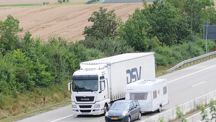 Der Verkehr fließt vorbei an Getreidefeldern und Photovoltaikmodulen des Solarparks.
