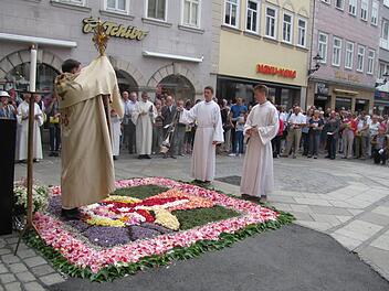 Pfarrer Tomasz Dzikowski beim eucharistischen Segen am Spitaltor. In der Nähe war das Georgen-Hospital und die dazugehörige Spitalkirche St. Georg. Wunderschön ist der aufwendig gestaltete Blumenteppich.  Foto: Martin Koch