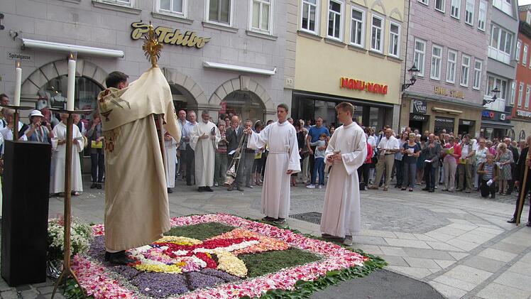 Pfarrer Tomasz Dzikowski beim eucharistischen Segen am Spitaltor. In der Nähe war das Georgen-Hospital und die dazugehörige Spitalkirche St. Georg. Wunderschön ist der aufwendig gestaltete Blumenteppich.  Foto: Martin Koch