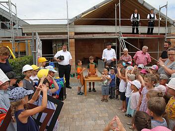 Das Richtfest am Kindergarten St. Martin in Eggolsheim: Die Kindergartenkinder sangen "Wer will fleißige Handwerker sehen?". Im Hintergrund Bürgermeister  Claus Schwarzmann und Pfarrer Daniel Schuster, oben wartet schon der Zimmermann, um den Richtspruch aufzusagen. Foto: Mathias Erlwein