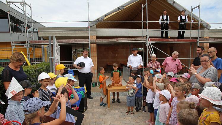 Das Richtfest am Kindergarten St. Martin in Eggolsheim: Die Kindergartenkinder sangen "Wer will fleißige Handwerker sehen?". Im Hintergrund Bürgermeister  Claus Schwarzmann und Pfarrer Daniel Schuster, oben wartet schon der Zimmermann, um den Richtspruch aufzusagen. Foto: Mathias Erlwein