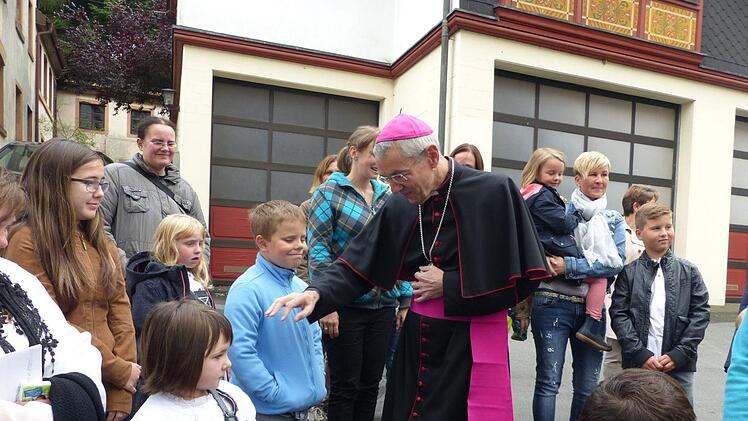 Erzbischof Ludwig Schick begrüßt die vor der Wartenfelser Kirche wartenden Kinder.