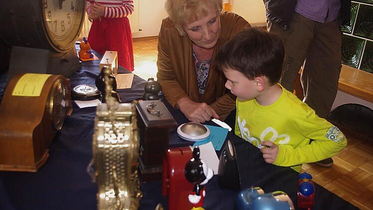 Kita-Leiterin Gertrud Schubert betrachtet mit Johannes die Uhren-Ausstellung.