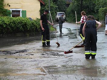 Alle packen mit an, um den mit dem starken Regen angespülten Schlamm von der Straße zu bekommen. Foto: Dagmar Besand