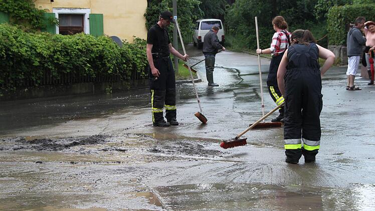 Alle packen mit an, um den mit dem starken Regen angespülten Schlamm von der Straße zu bekommen. Foto: Dagmar Besand