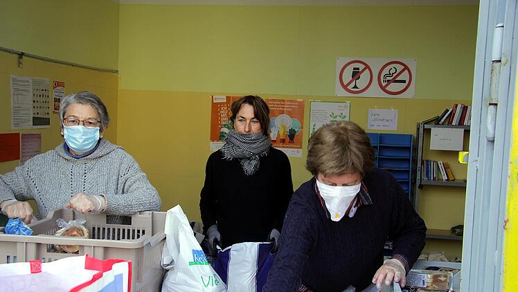 Mit Mundschutz und Handschuhen geben die Helfer der Tafel vorgepacke Lebensmitteltüten heraus. Foto: Bastian Reusch