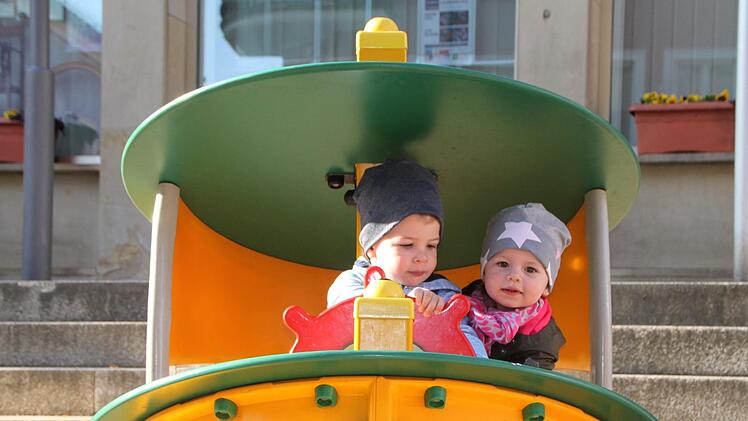 Am Steuer eines Spielgeräts, das auf dem Marktplatz aufgebaut ist: Brian Jordan aus Weichersbach geht mit seiner Mama manchmal Einkaufen in Bad Brückenau, hauptsächlich im Fachmarktzentrum.    Mayra Wähner aus Zeitlofs besucht gerne Oma und Opa.  Foto:  Ulrike Müller