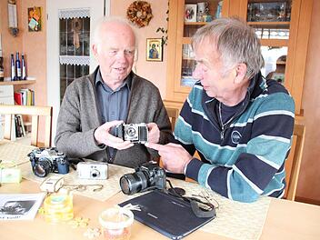 Willibald Jungkunz (links) und Paul Hader sind zwei langjährige Berichterstatter. Willibald Jungkunz zeigt seinen ersten Fotoapparat, bei dem man noch alles manuell einstellen musste, der noch nicht einmal einen Belichtungsmesser hatte. Auf dem Tisch liegen weitere Fotoapparate sowie Paul Haders Tablet-PC, mit dessen Hilfe er Texte und Bilder an den FT mailt. Foto: Friedwald Schedel
