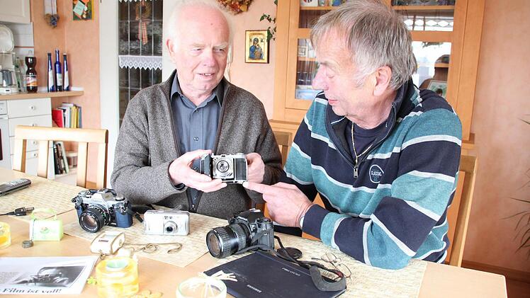 Willibald Jungkunz (links) und Paul Hader sind zwei langjährige Berichterstatter. Willibald Jungkunz zeigt seinen ersten Fotoapparat, bei dem man noch alles manuell einstellen musste, der noch nicht einmal einen Belichtungsmesser hatte. Auf dem Tisch liegen weitere Fotoapparate sowie Paul Haders Tablet-PC, mit dessen Hilfe er Texte und Bilder an den FT mailt. Foto: Friedwald Schedel