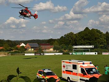 Solche Bilder will man auf einem Fu&szlig;ballplatz nicht sehen: Der Notarzt und die Helfer vom Bayerischen Roten Kreuz k&uuml;mmern sich hinter dem Rettungswagen um den  verletzten Arnsteiner Manuel Will. Zudem fliegt gerade der Hubschrauber ein.  Foto: Gunther Czepera