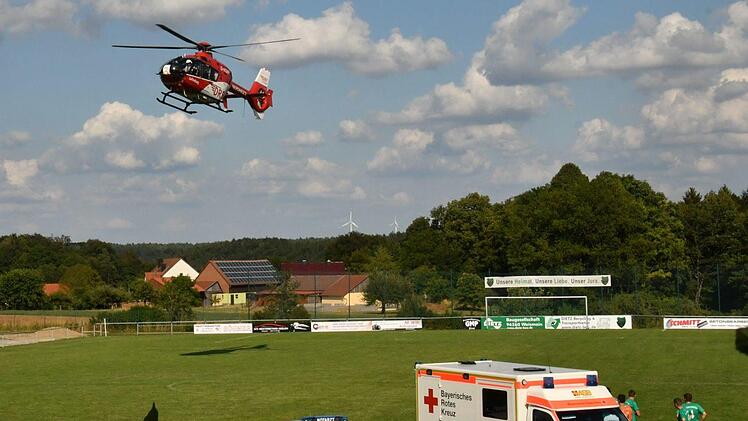 Solche Bilder will man auf einem Fu&szlig;ballplatz nicht sehen: Der Notarzt und die Helfer vom Bayerischen Roten Kreuz k&uuml;mmern sich hinter dem Rettungswagen um den  verletzten Arnsteiner Manuel Will. Zudem fliegt gerade der Hubschrauber ein.  Foto: Gunther Czepera