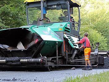Auf offener Strecke durch den Neuwirtshäuser Forst trägt der  Asphaltfertiger die Asphaltschicht über die gesamte Straßenbreite auf. So entstehen keine Nähte, und die Bundesstraße ist dem Schwerlastverkehr besser gewachsen. Fotos: Benedikt Borst