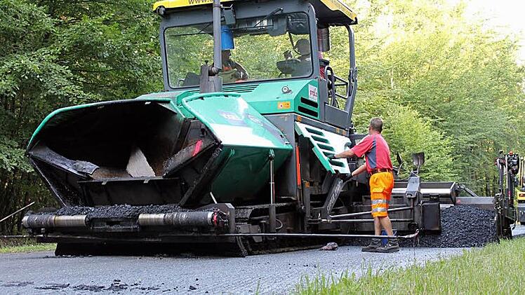 Auf offener Strecke durch den Neuwirtshäuser Forst trägt der  Asphaltfertiger die Asphaltschicht über die gesamte Straßenbreite auf. So entstehen keine Nähte, und die Bundesstraße ist dem Schwerlastverkehr besser gewachsen. Fotos: Benedikt Borst
