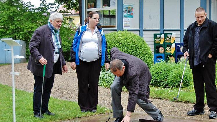 Bürgermeister Wolfgang Back (l.) schaffte mit zwei, Pfarrer Michael Kubatko (Mitte) mit drei Schlägen den Ball ins Loch; Zuschauer waren Jeanette Humbek-Hönicke, Vorsitzende des Minigolfclubs "Stahlquelle" und Ingo Graf von Mainberg, Lehrwart im Bayerischen Minigolfsport-Verband. Fotos: Sigismund von Dobschütz