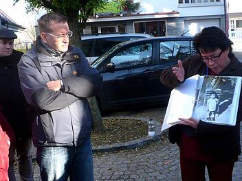 Christiane Kolbet erläutert Einzelheiten wie hier zu einem Foto der kleinen Erna Fleischhauer vor dem Marterl, das jetzt im Vorgarten des Rathauses steht. Foto: Johanna Blum