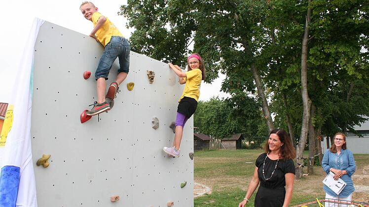 Cordula Atzhorn (im schwarzen Kleid) machte sich und der Schule zum Abschied eine Boulderwand zum Geschenk, die im Herbst aufgestellt wird. An einem Teilstück der Wand durften Leonie und Richard schon einmal ihr Geschick testen.