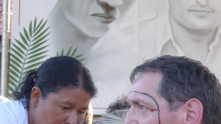 Während ihrer kürzlichen Brasilienreise auf den Spuren Rudolf Lunkenbeins wurden seine Verwandten zur Begrüßung durch ehrenvolle Bemalung geschmückt. Im Hintergrund zeigen die Porträts Pater Rudolf (rechts) und seinen Freund Simao Bororo.  Foto: Adalbert Kopp