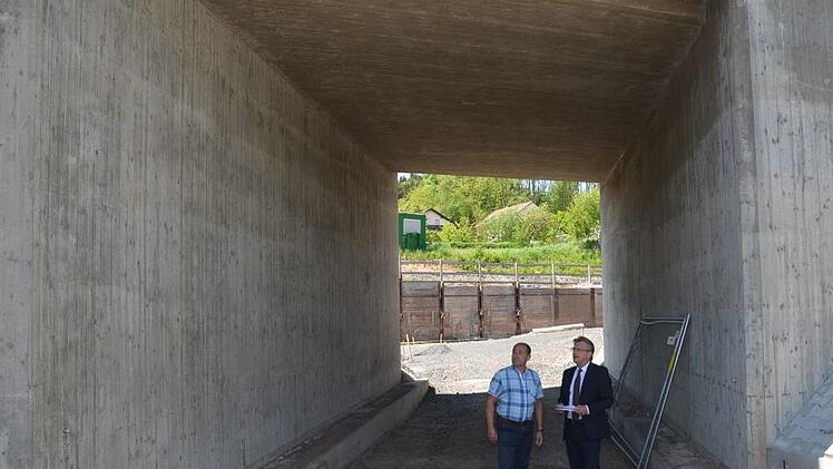 Die fertiggestellte sanierte Bahnüberführung ist nicht das Problem der Maxschachtstraße, sondern das dahinter vom Hang  austretende Schichtenwasser, erklären Bauamtsleiter Günter Hempfling (links) und Bürgermeister Rainer Detsch vor Ort.  K.- H. Hofmann