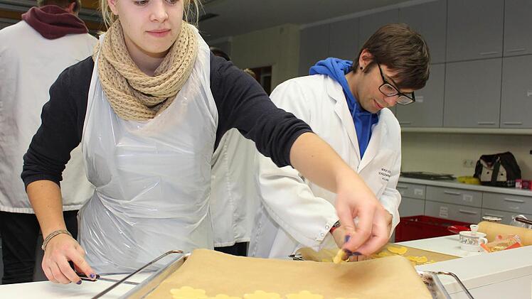 Alina Gack sticht die Butterplätzchen aus und Schülersprecher Dominik Miskolci bestreicht sie mit Eigelb und legt Mandeln darauf.