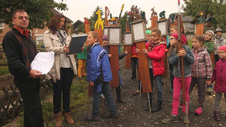 In einem Zug trugen die Schüler ihre Tafeln von der Schule zur Streuobstwiese. Peter Kirchner und Antje Schorn (von links) warben dafür, den Streuobstlehrpfad immer wieder mal zu besuchen. Foto: Günther Geiling