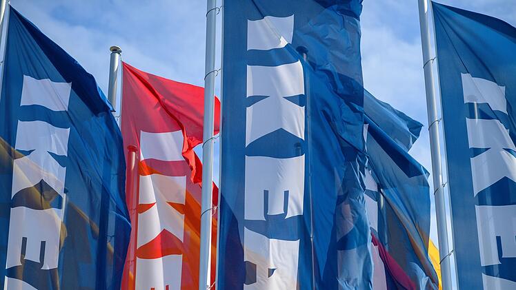 Blau-rote Fahnen mit Ikea-Logo wehen im Wind vor blauem Himmel. Sie symbolisieren die Ankunft eines neuen Möbelhauses nahe Bamberg.