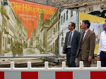 Die Bildtafeln erzählen eine Geschichte. Sie nehmen die Betrachter mit auf eine Reise in die Vergangenheit, werfen aber auch einen Blick in die Zukunft. Flächenmanager Christoph Hagen, Bürgermeister Peter Kornell und Tourismuschef Marco Maiberger freuen sich über die gelungene Verschönerung der Bauruinen-Ansicht.  Foto: Peter Pfannes