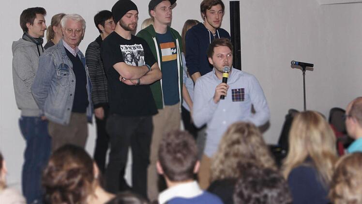 Alle Poeten auf einer Bühne vereint; in der vorderen Reihe stehen die drei Finalisten Flo Langbein (von links mit schwarzer Mütze), Andreas Rebholz und Julian Kalks. Christian Ritter fordert das Publikum zu einem Zwei-Sekunden-Applaus auf. Foto: Sarah Dann