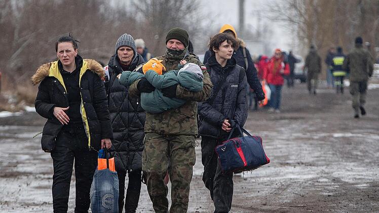Ein polnischer Soldat trägt ein Kind, während Frauen und Kinder nach ihrer Flucht aus der Ukraine am Grenzübergang in Medyka, Polen, zu einem Zug in Richtung Krakau gehen. Nach Angaben der Vereinten Nationen hat der russische Angriff zwei Millionen Menschen gezwungen, aus der Ukraine zu fliehen.
