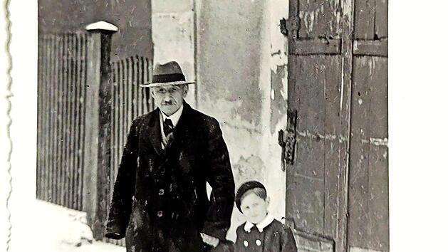 Die Fotografie von etwa 1949 zeigt Albert Schloß vor seinem Wohnhaus in Mühlhausen, zusammen mit dem etwa sechsjährigen Ralf Kriegel, dem Enkel von Frau Preussner, die eine Freundin der Eheleute Schloß gewesen ist.
