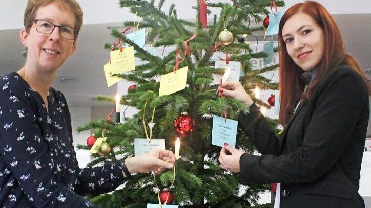 Kathrin Reif vom Bürgerzentrum (l.) und Daniela Bauer hängen die letzten Wunschzettel an den Geschenkebaum, der ab heute in der Sparkassen-Filiale Forchheim-Nord steht. Foto: Johannes Höllein