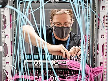 Systemadministrator Alexander Landmann zieht Lichtwellenleiter aus den Massenspeichergeräten im Rechenzentrum der Deutschen Bahn. Zwei Jahre früher als geplant hat die Bahn ihre eigene Rechenzentren abgeschaltet und ihre komplette IT in die Cloud verlagert. Foto: Britta Pedersen, dpa