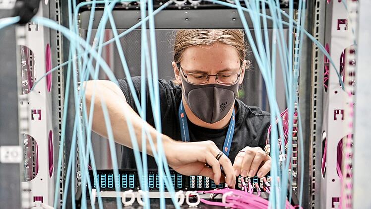 Systemadministrator Alexander Landmann zieht Lichtwellenleiter aus den Massenspeichergeräten im Rechenzentrum der Deutschen Bahn. Zwei Jahre früher als geplant hat die Bahn ihre eigene Rechenzentren abgeschaltet und ihre komplette IT in die Cloud verlagert. Foto: Britta Pedersen, dpa