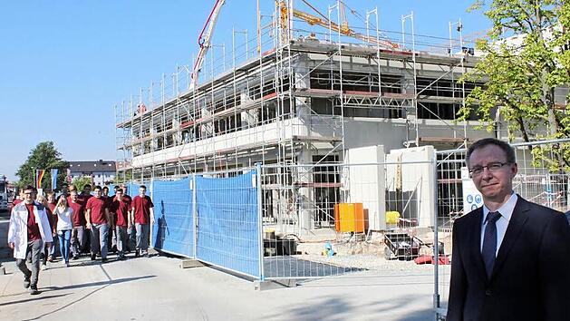 Gesch&auml;ftsf&uuml;hrer Herbert Drechsel vor der im Bau befindlichen neuen Produktionshalle. Mit im Bild der Unternehmensnachwuchs aus der Lehrwerkstatt mit deren Leiter. Foto: Popp